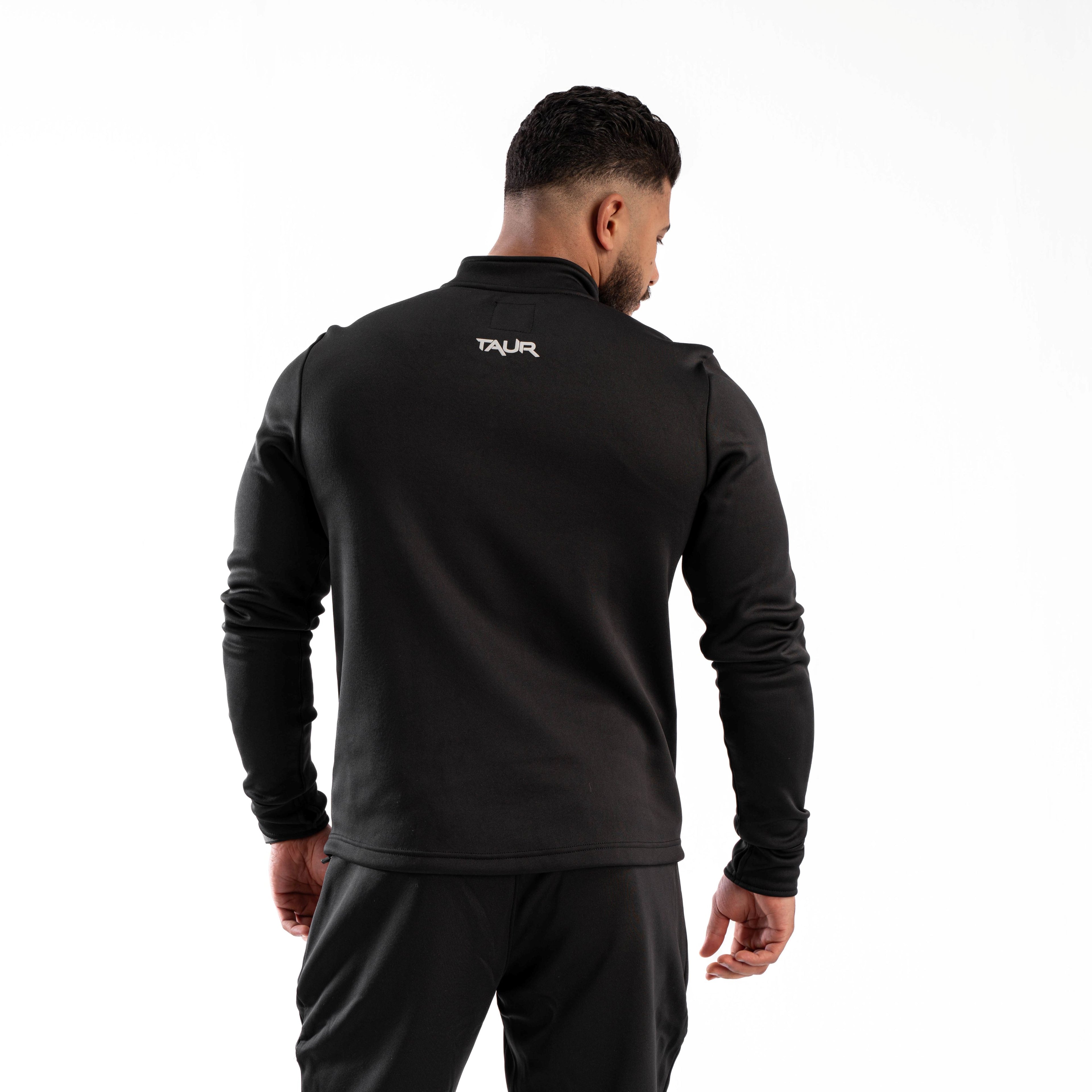 Man wearing a black tracksuit with 'Taur' branding on the back against a white background